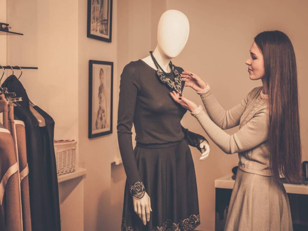 Young woman looking at necklace on mannequin in showroom